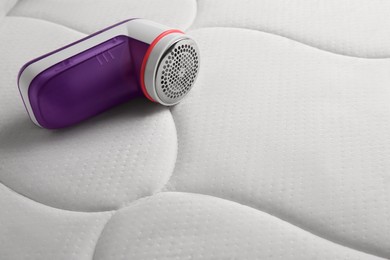Photo of Modern fabric shaver on mattress with lint. Space for text
