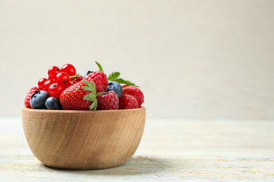 Photo of Mix of different fresh berries in bowl on wooden table. Space for text