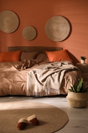 Bed with orange and brown linens in stylish room