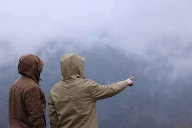 Man and woman in raincoats enjoying mountain landscape