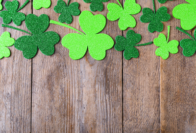 Photo of Flat lay composition with clover leaves on wooden table, space for text. St. Patrick's Day celebration