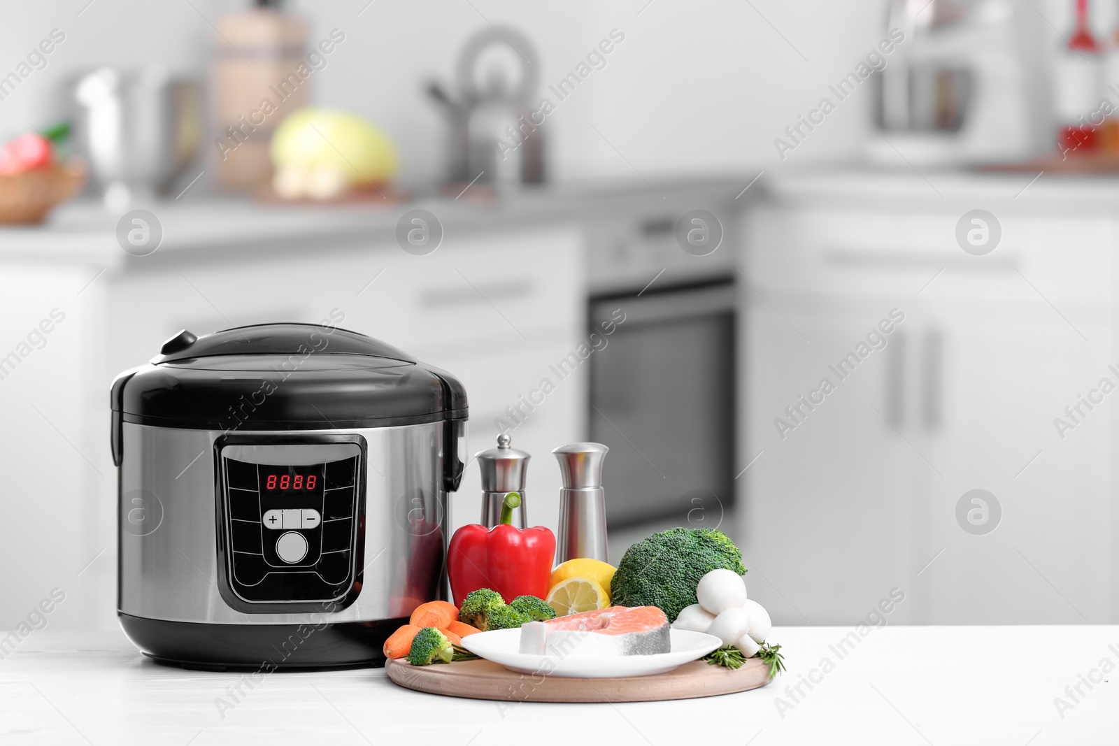 Photo of Modern multi cooker and products on table in kitchen. Space for text