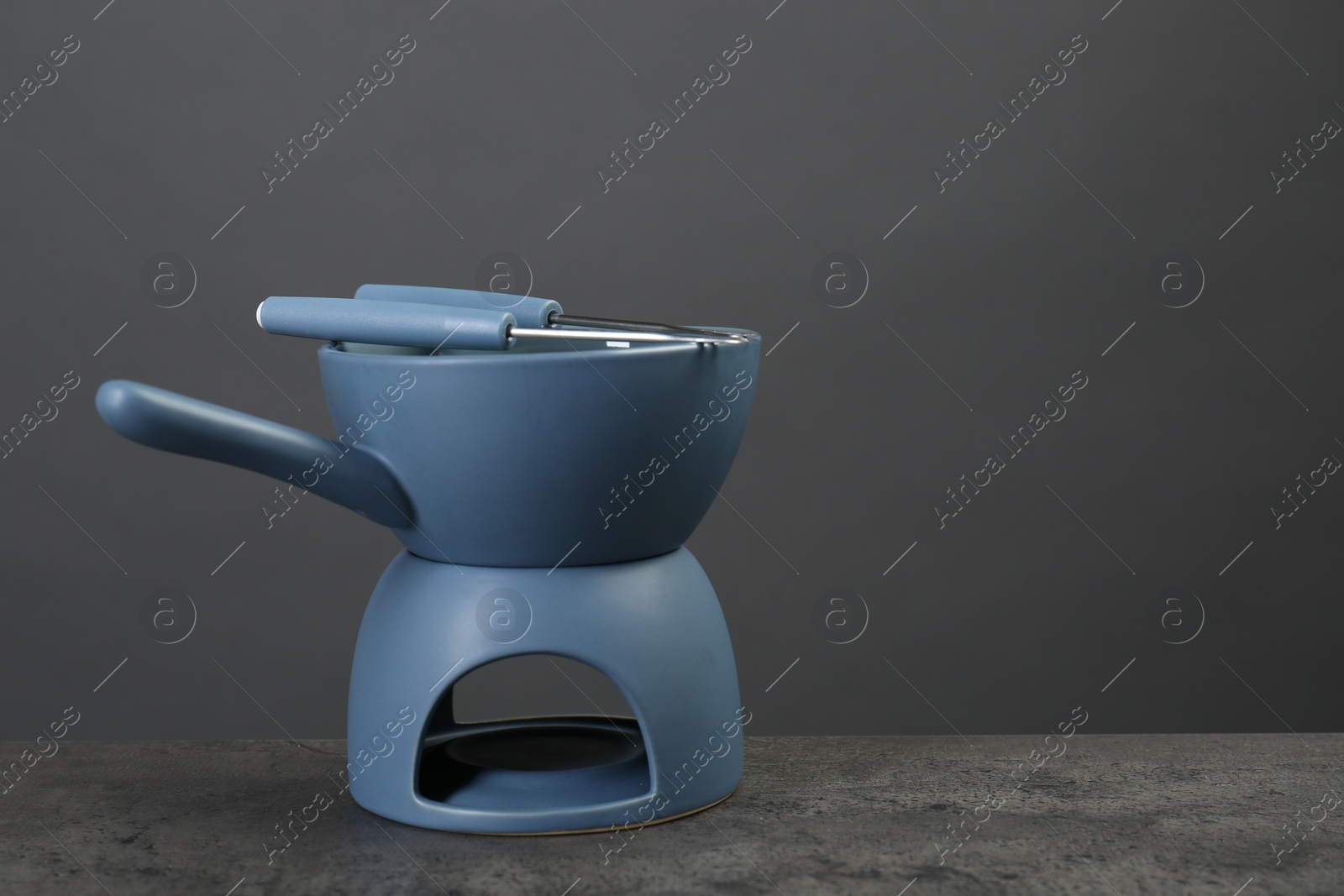 Photo of Fondue set on grey textured table, space for text