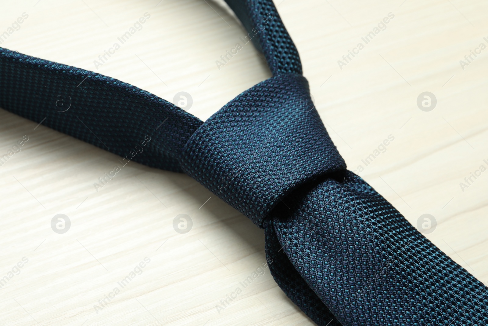 Photo of One blue necktie on white wooden table, closeup