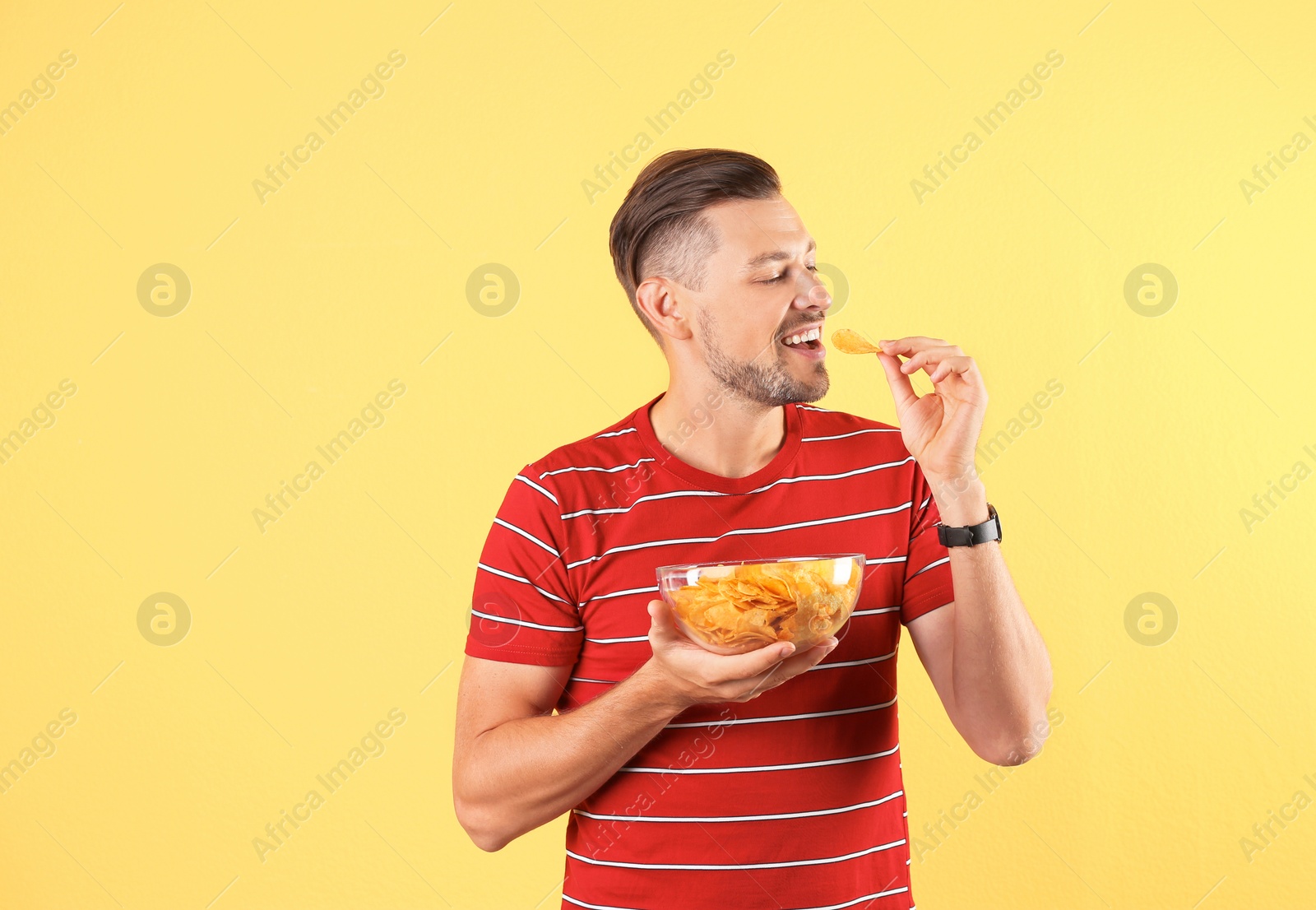 Photo of Man eating potato chips on color background