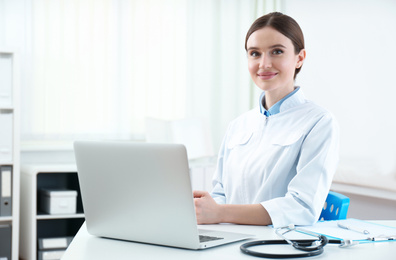 Portrait of young female doctor in white coat at workplace