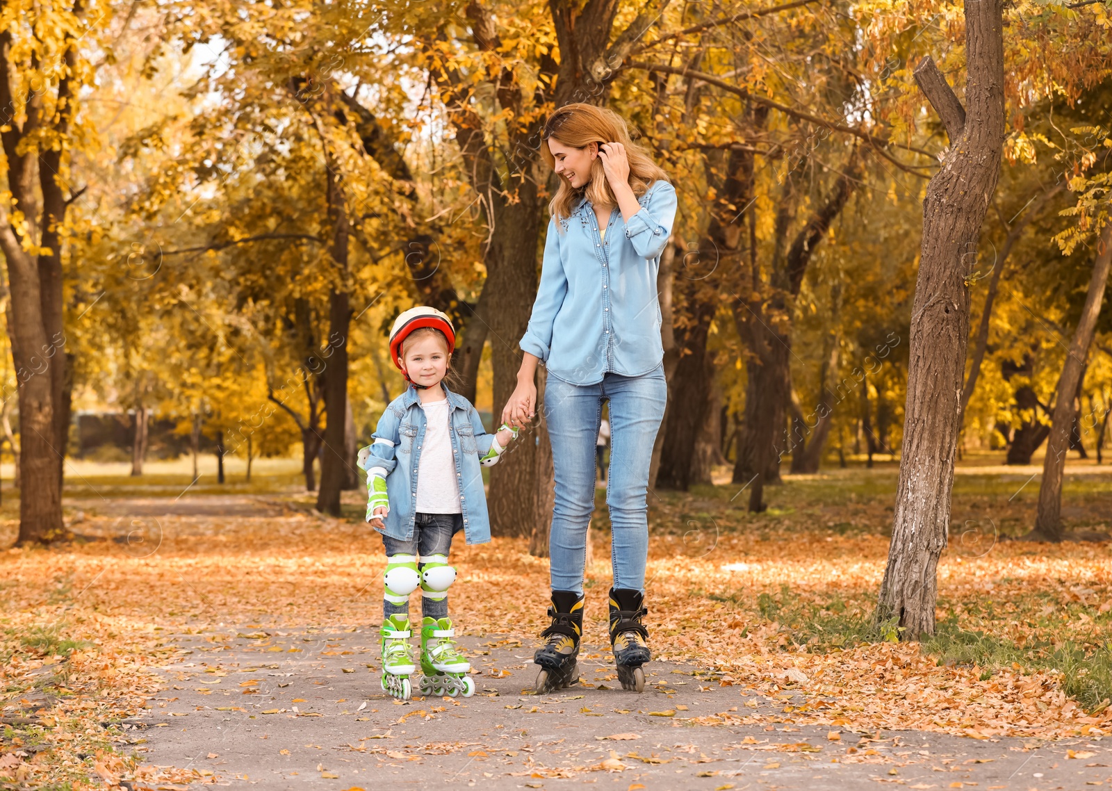 Photo of Mother and her daughter roller skating in autumn park
