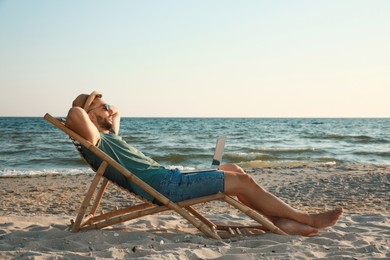 Photo of Man with laptop relaxing in deck chair on beach