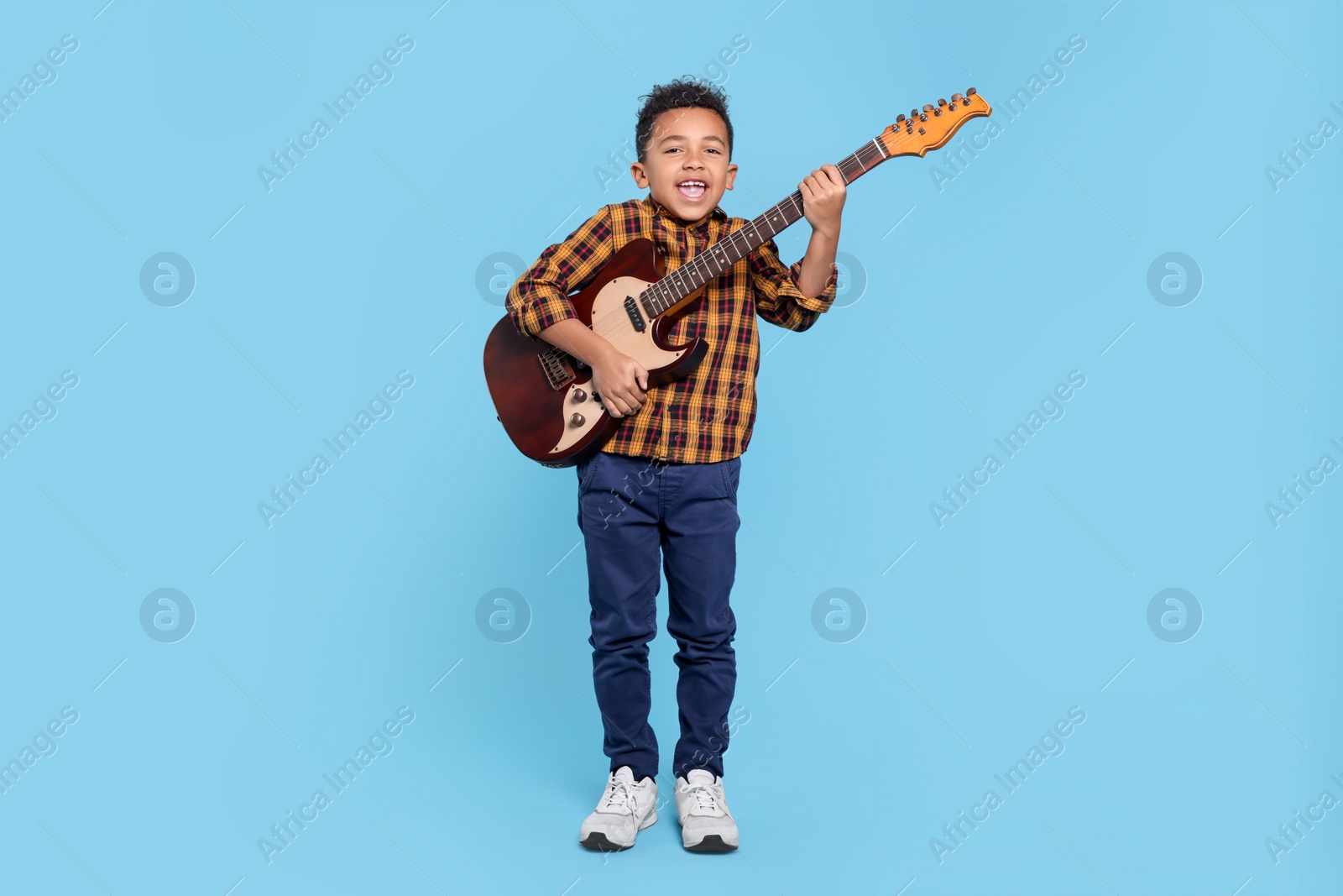 Photo of Cute African-American boy with electric guitar on turquoise background