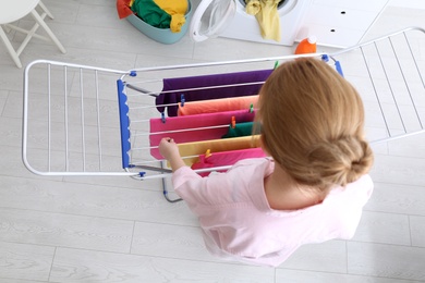 Woman hanging clean laundry on drying rack indoors, above view
