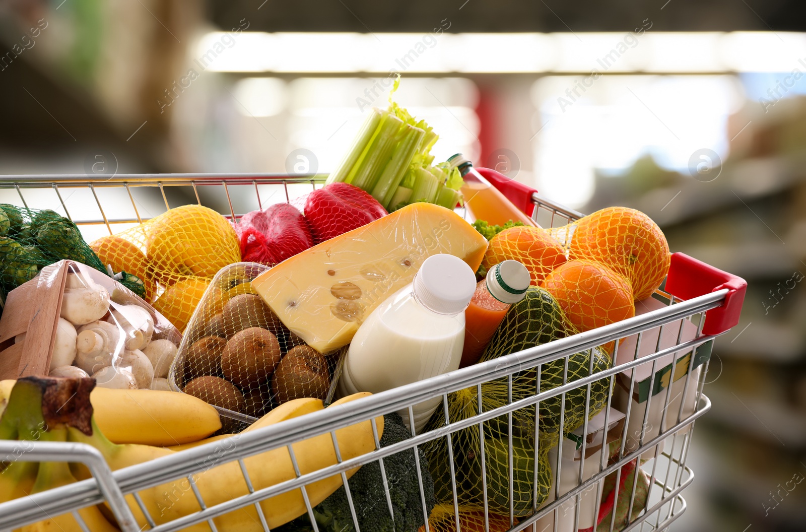 Image of Shopping cart with different groceries in supermarket