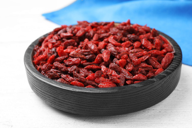 Photo of Dried goji berries on white wooden table, closeup