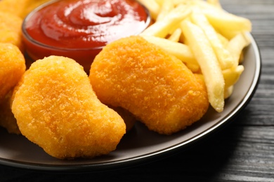 Photo of Tasty fried chicken nuggets served on black wooden table, closeup