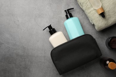 Compact toiletry spa bag and different cosmetic products on grey textured background, flat lay. Space for text