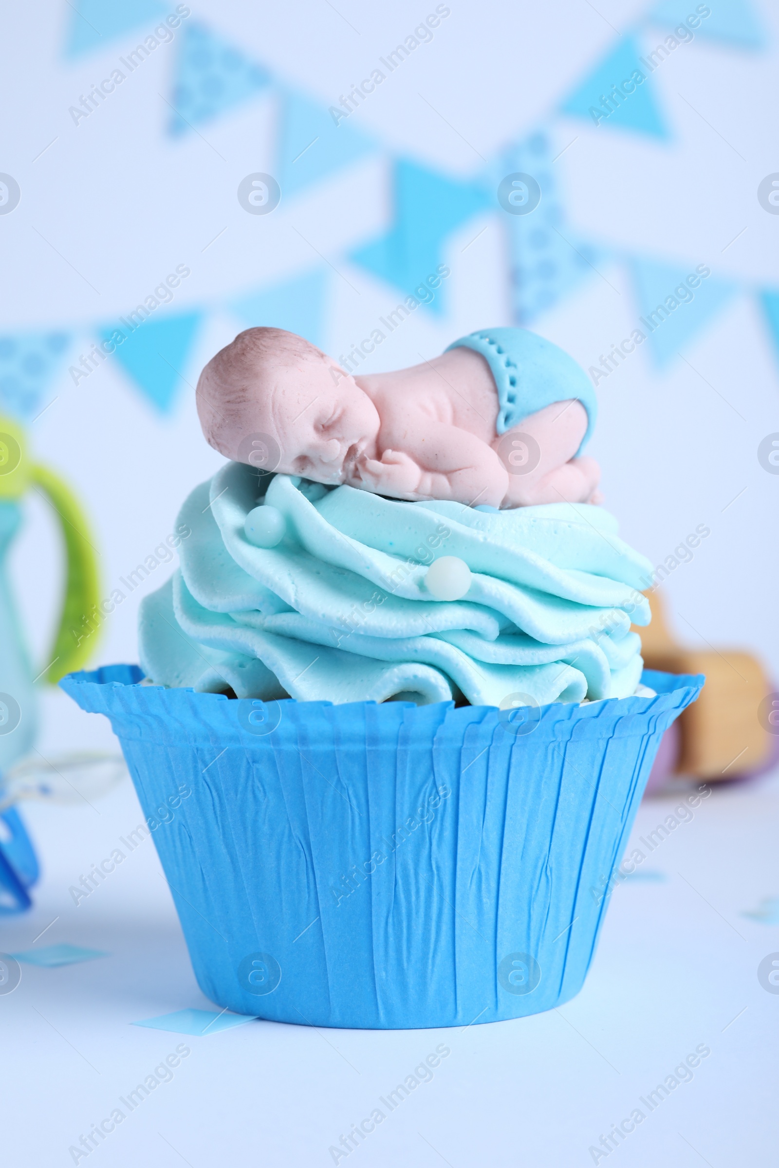 Photo of Beautifully decorated baby shower cupcake for boy with cream and topper on light background.