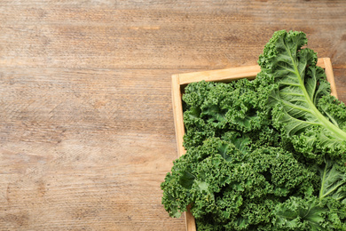 Fresh kale leaves on wooden table, top view. Space for text