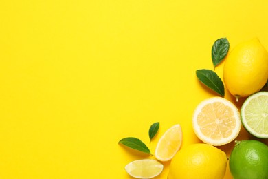 Photo of Fresh ripe lemons, limes and green leaves on yellow background, flat lay. Space for text