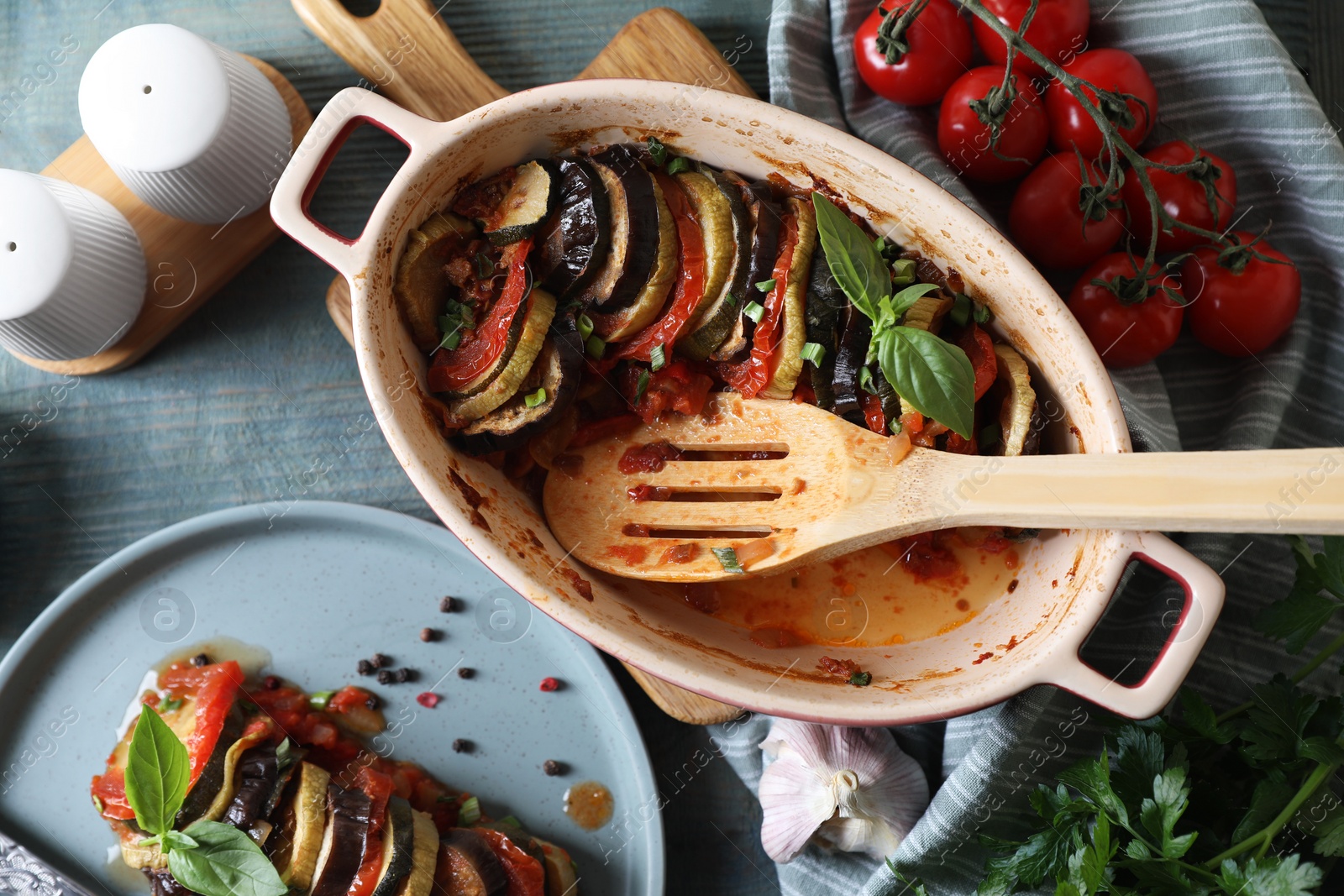 Photo of Delicious ratatouille served with basil on grey wooden table, flat lay