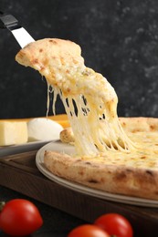 Photo of Taking piece of delicious cheese pizza at table, closeup