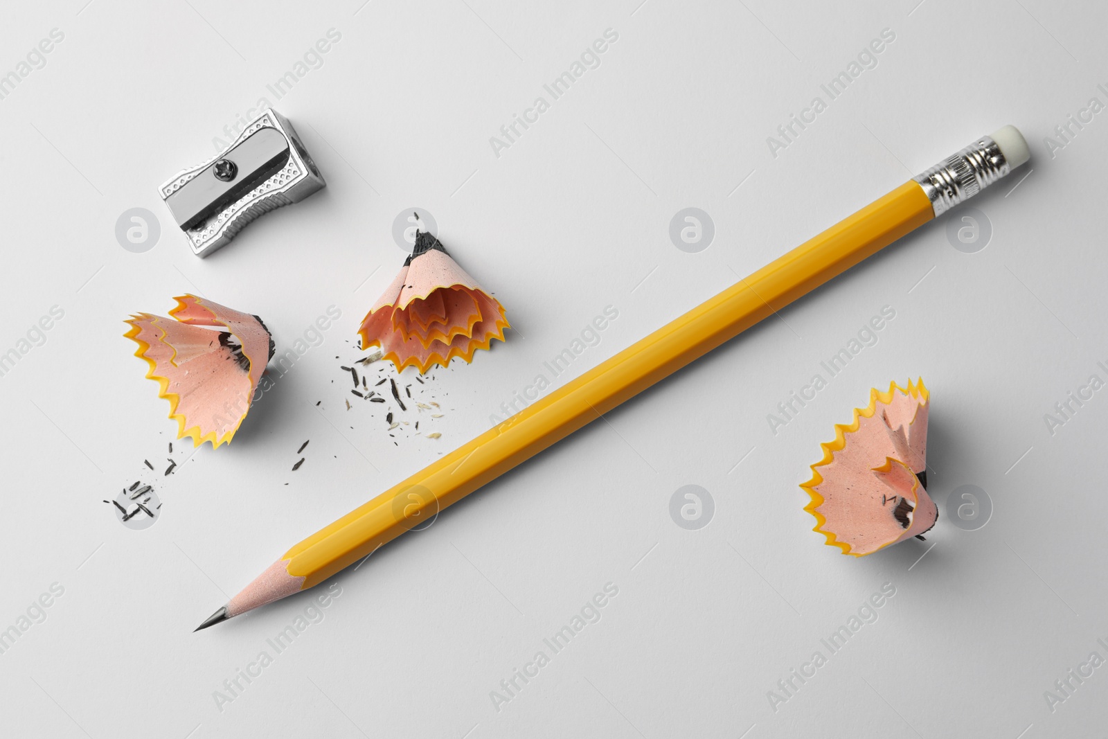 Photo of Graphite pencil, shavings and sharpener on white background, flat lay