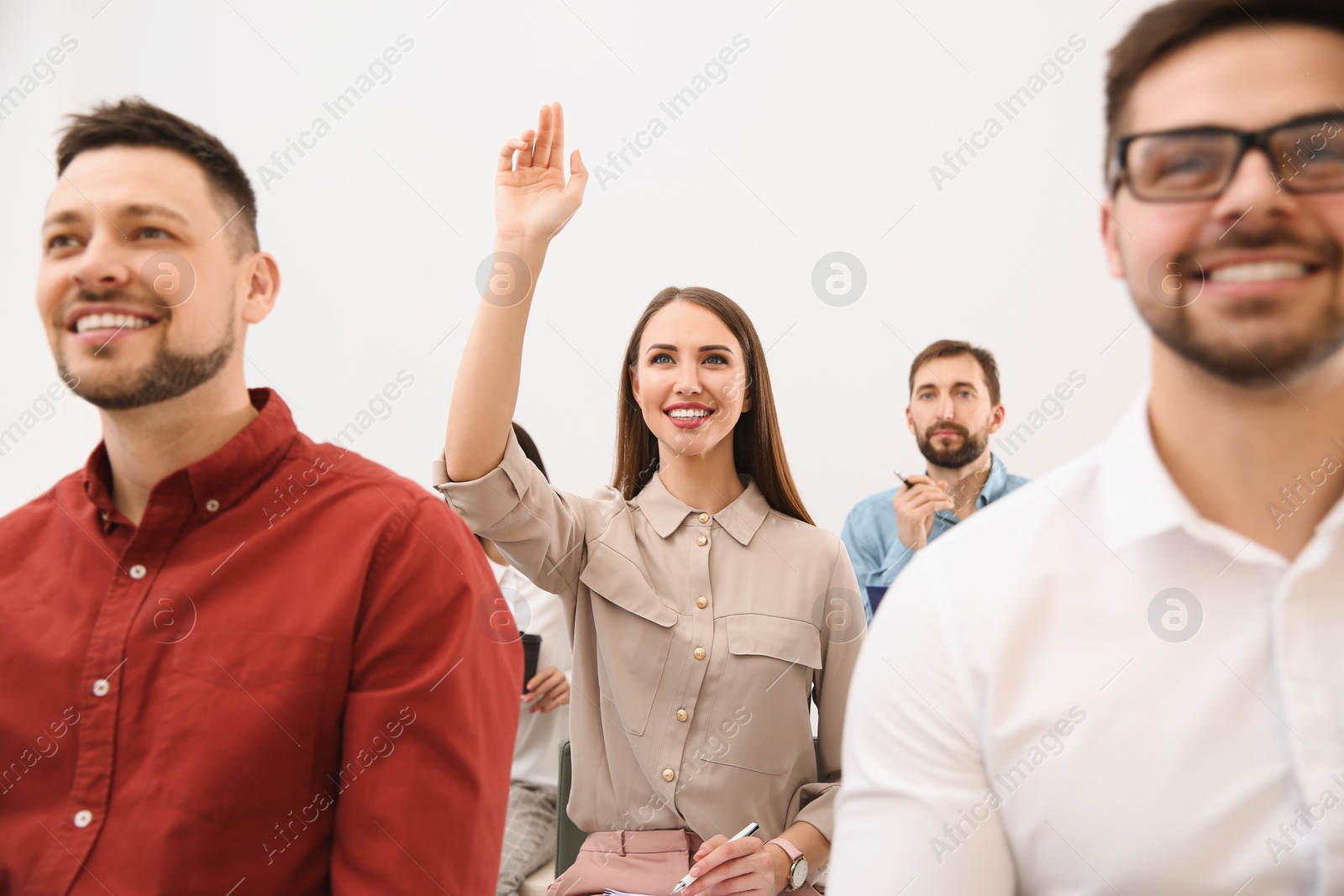 Photo of Young woman raising hand to ask question at business training on white background