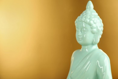 Photo of Buddha statue on golden background, closeup. Space for text