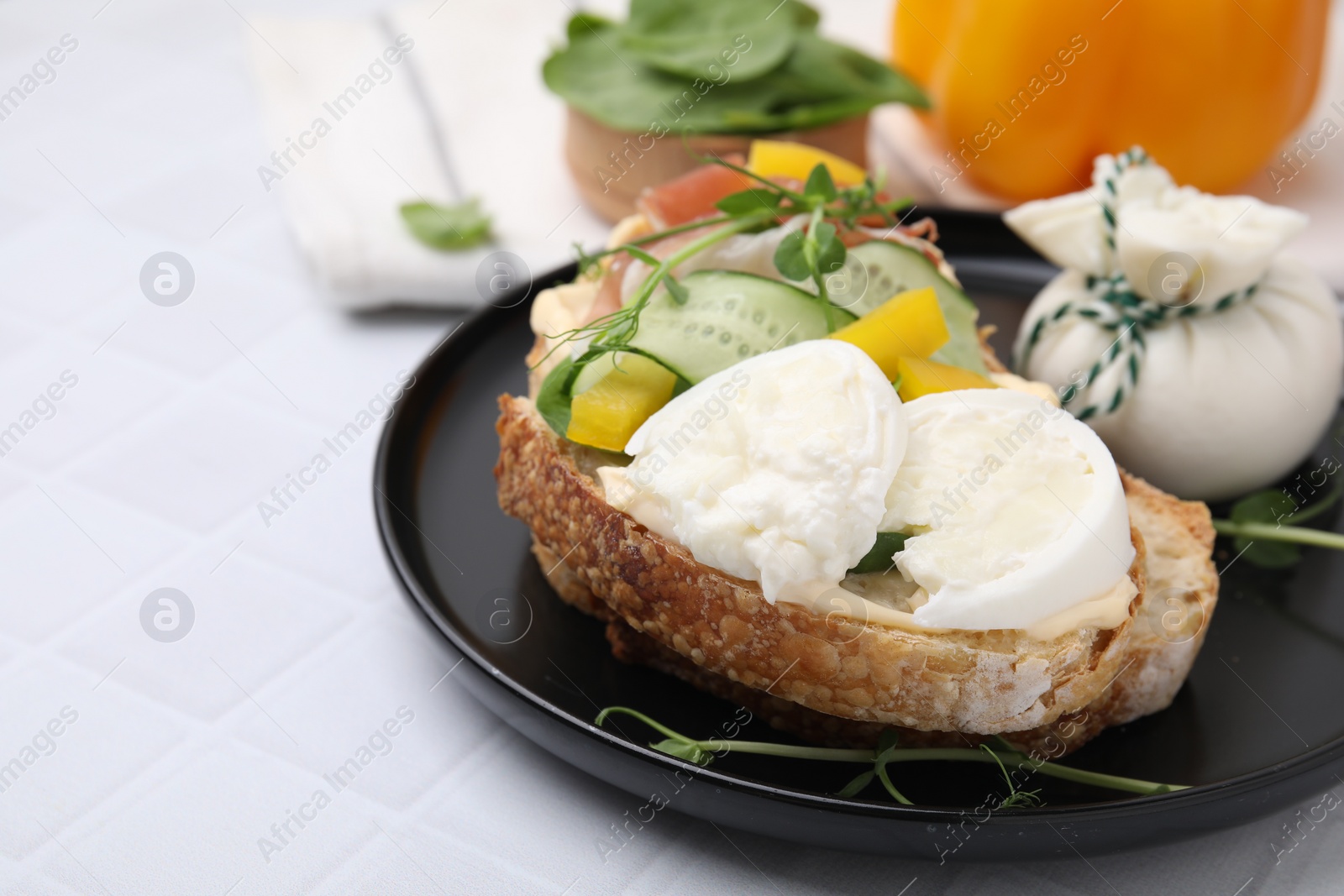 Photo of Tasty sandwich with burrata cheese, prosciutto and vegetables on white table, closeup