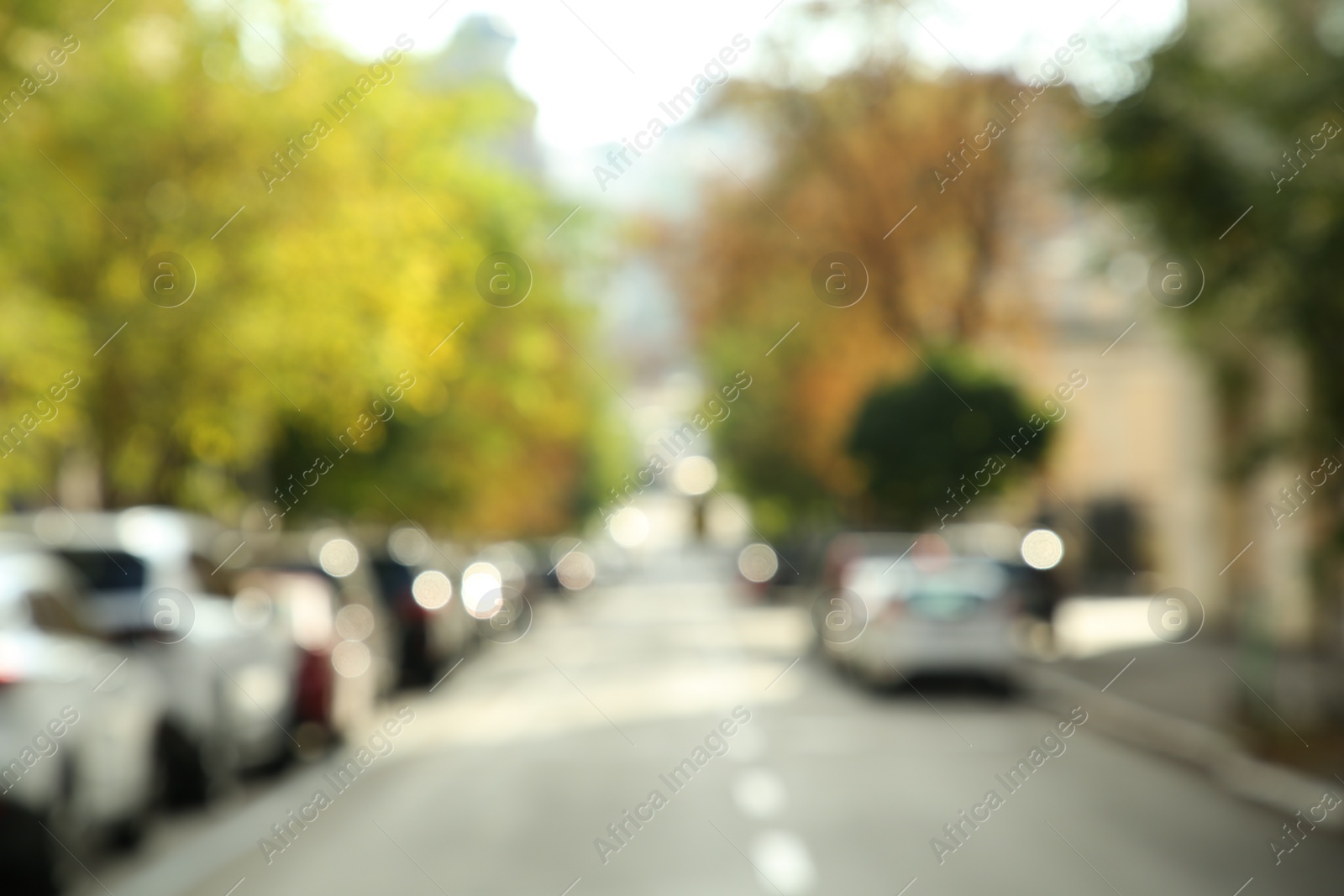 Photo of Blurred view of quiet city street with cars on road on sunny day