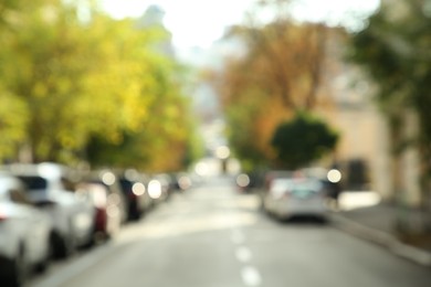 Blurred view of quiet city street with cars on road on sunny day