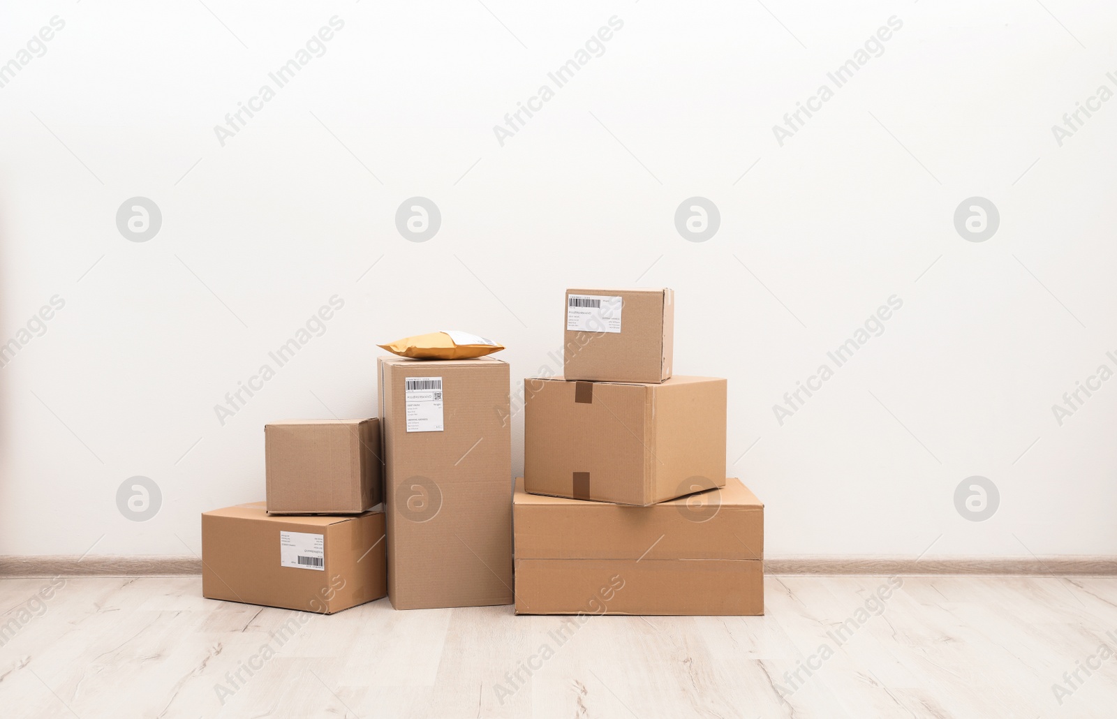 Photo of Stacked parcel boxes on floor against light wall