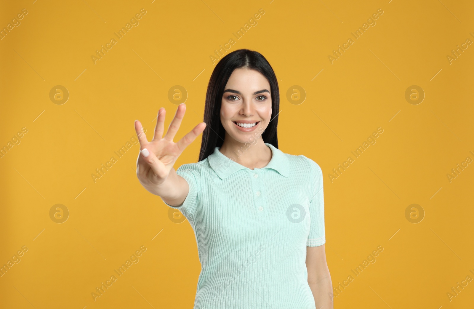 Photo of Woman showing number four with her hand on yellow background