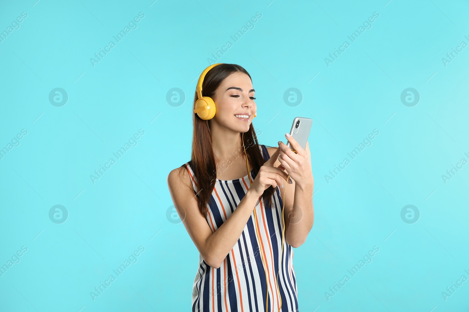 Photo of Beautiful young woman listening to music with headphones on color background