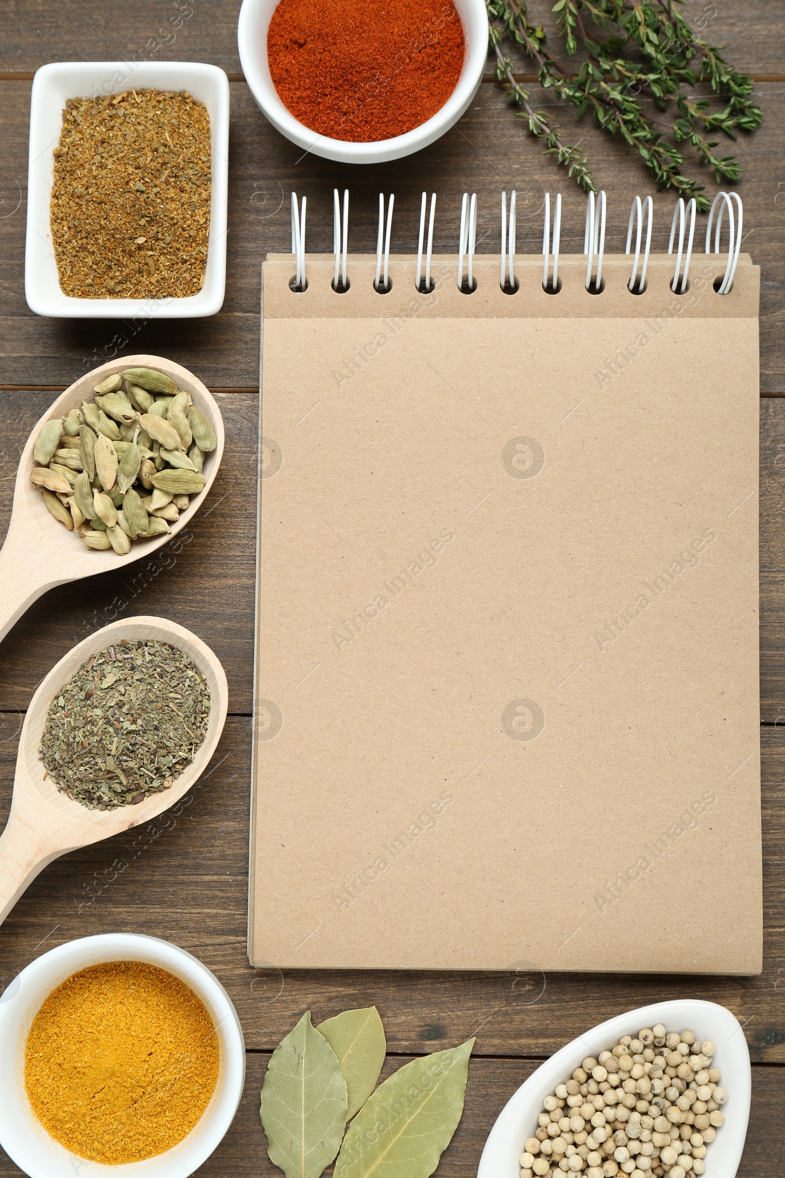 Photo of Blank recipe book and different ingredients on wooden table, flat lay. Space for text