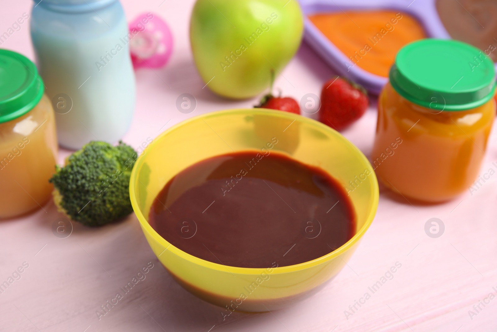 Photo of Healthy baby food and ingredients on pink wooden table