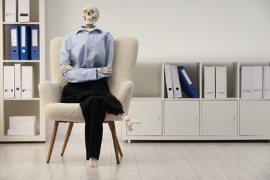 Waiting concept. Human skeleton sitting in armchair at office, space for text