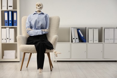 Photo of Waiting concept. Human skeleton sitting in armchair at office, space for text