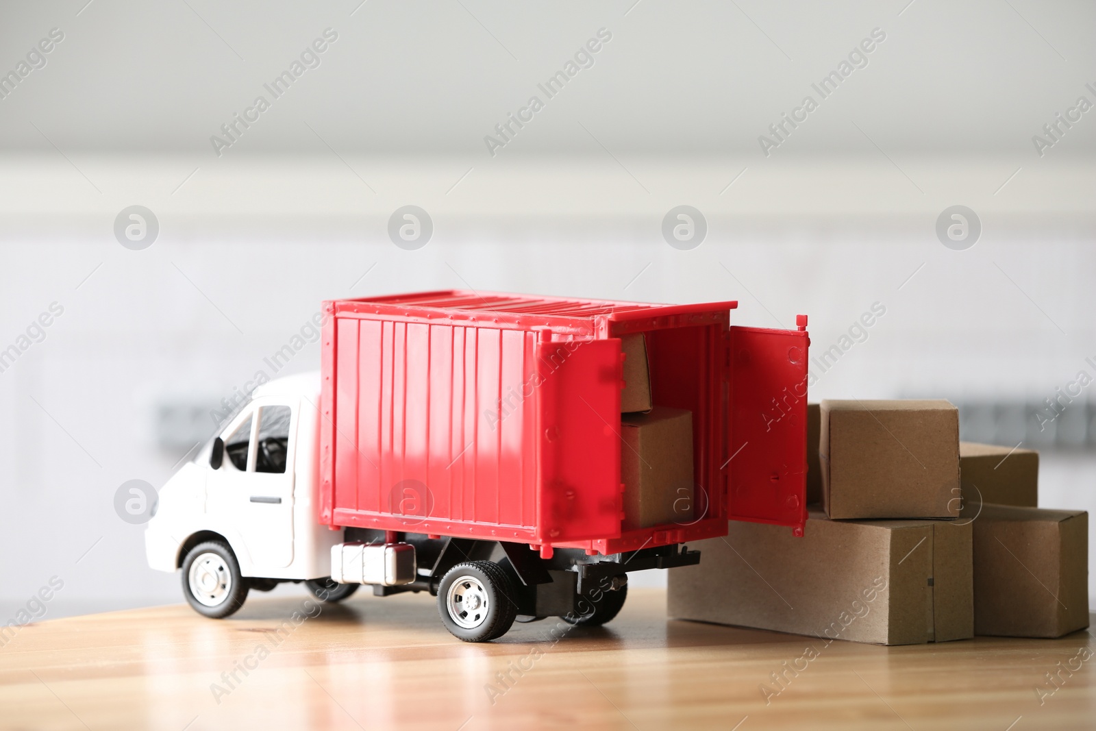 Photo of Toy truck and cardboard boxes on table against blurred background. Courier service