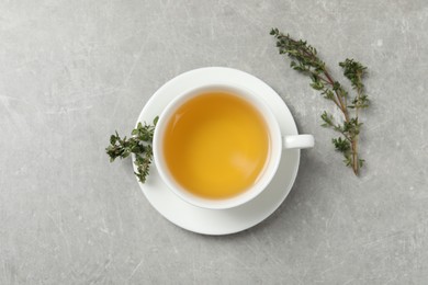 Aromatic herbal tea with thyme on light grey table, flat lay