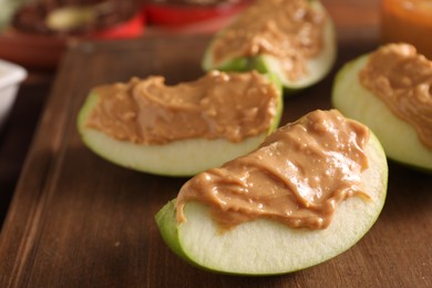 Slices of fresh apple with nut butter on wooden board, closeup