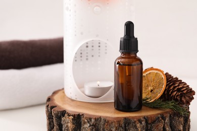 Photo of Aroma lamp and coniferous essential oil on stump
