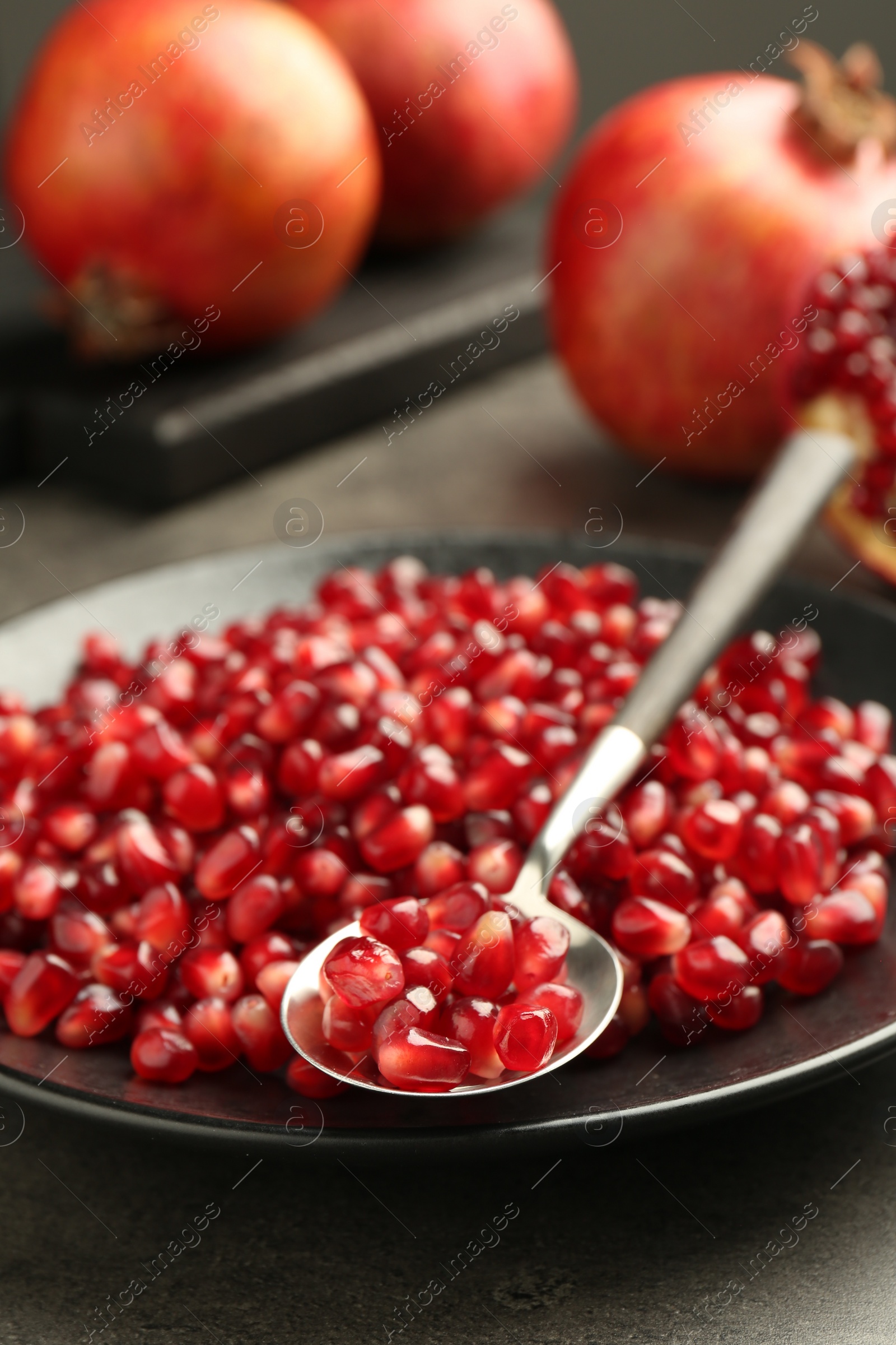 Photo of Ripe juicy pomegranate grains on grey table