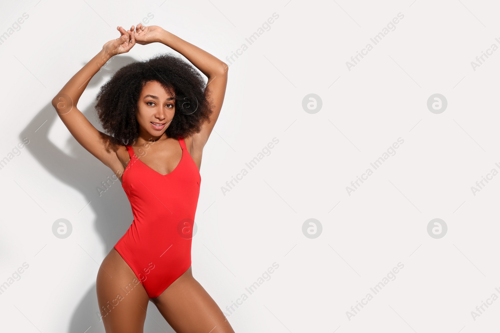 Photo of Beautiful woman in red one-piece summer swimsuit on white background, space for text