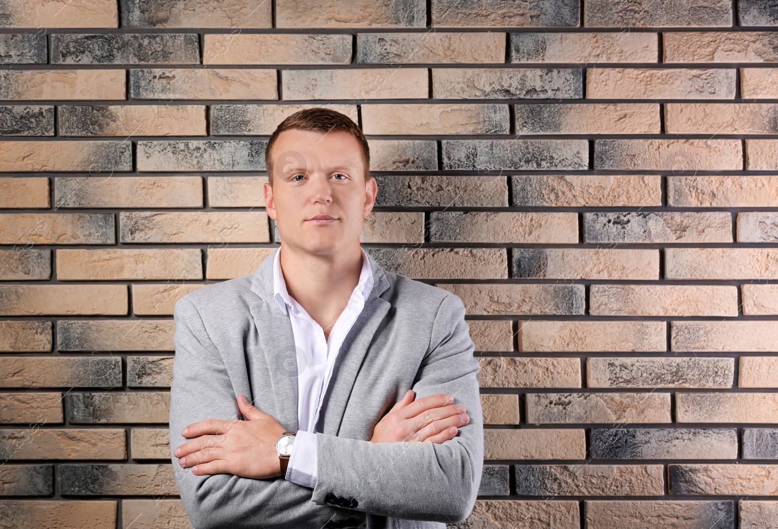 Photo of Handsome young man in suit near brick wall background