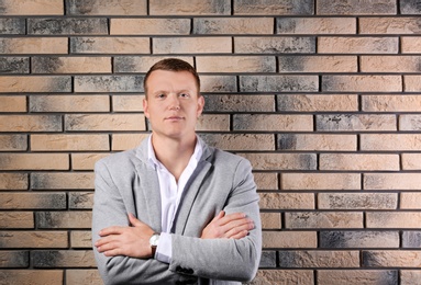 Photo of Handsome young man in suit near brick wall background