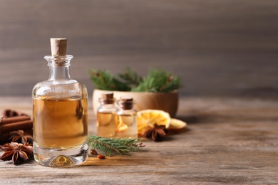 Anise essential oil and spices on wooden table, space for text