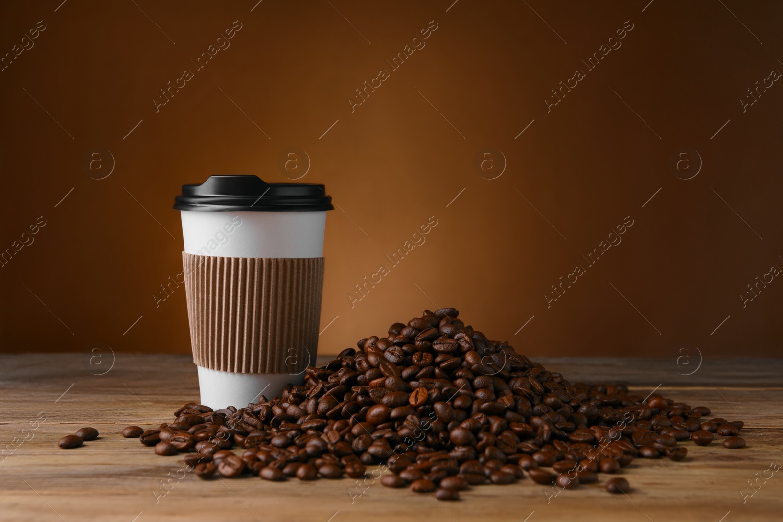 Photo of Coffee to go. Paper cup and roasted beans on wooden table, space for text