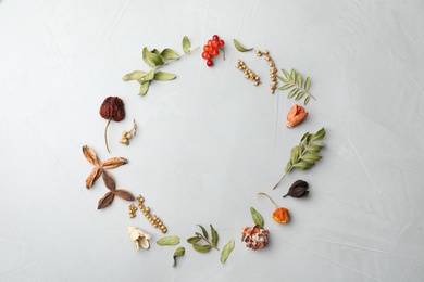 Photo of Dried flowers, leaves and berries arranged in shape of wreath on light grey background, flat lay with space for text. Autumnal aesthetic