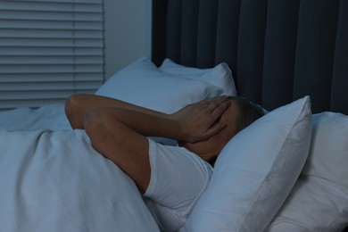 Woman suffering from headache in bed at night