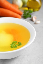 Delicious chicken bouillon with parsley on light grey textured table, closeup
