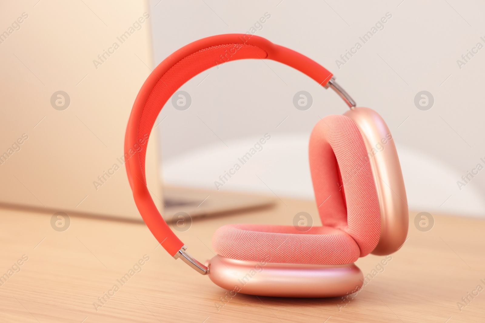 Photo of Modern headphones and laptop on wooden table